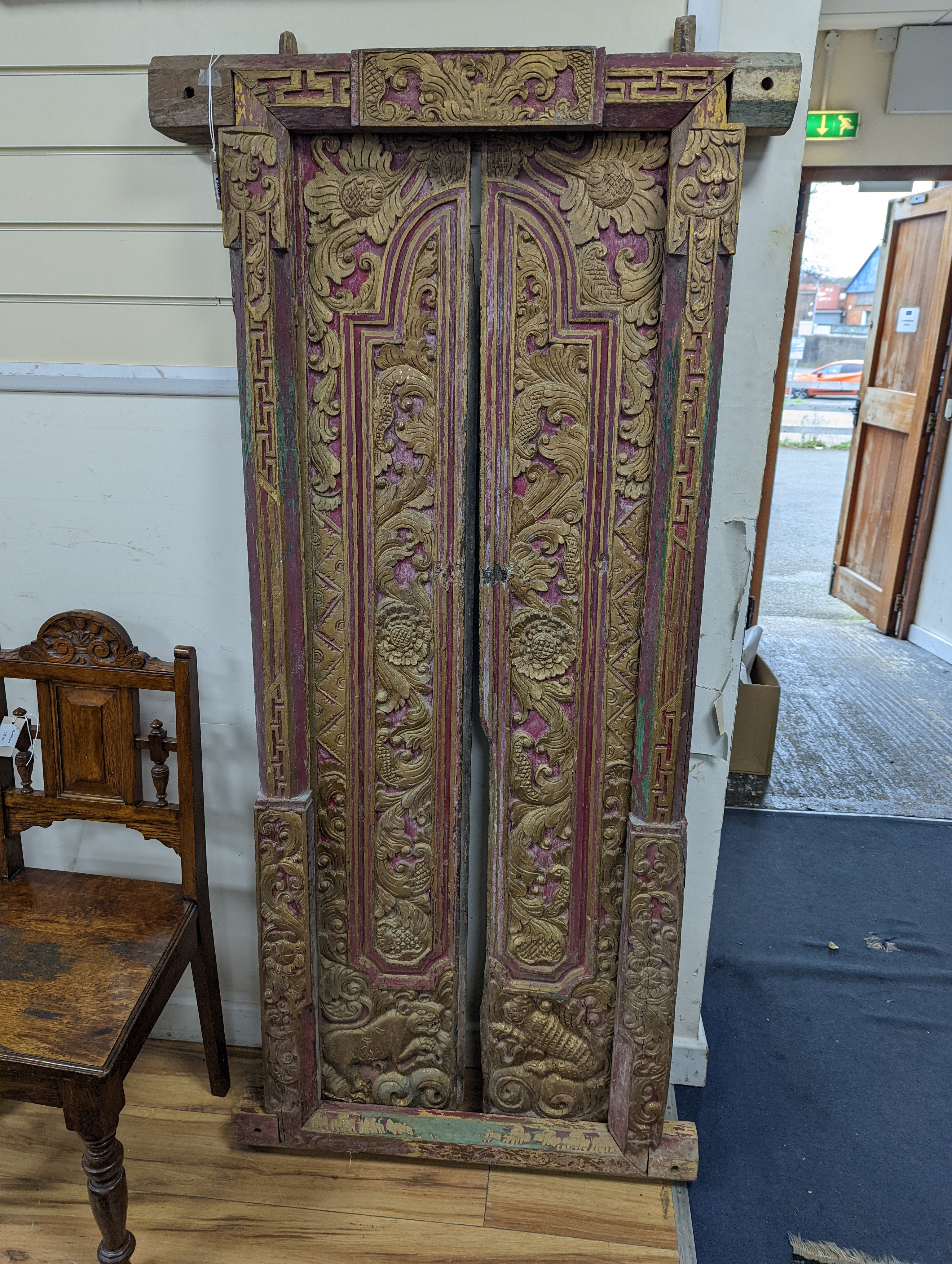 A Balinese carved giltwood door and frame, painted and gilded, width 83cm, height 174cm